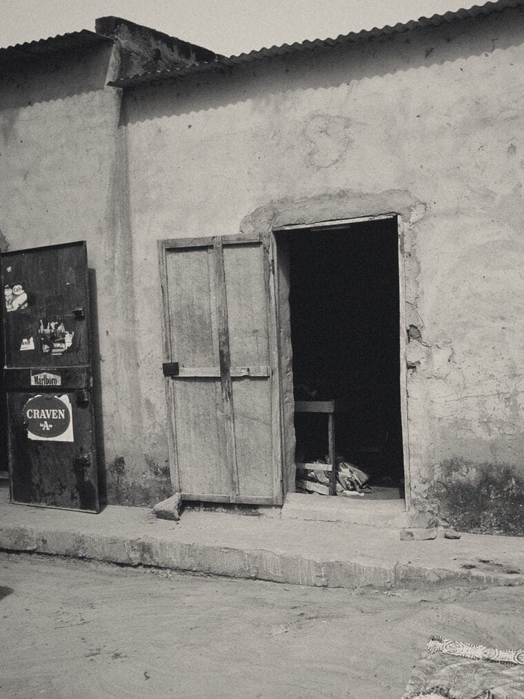Portes ouvertes dans un mur nu le long d'un trottoir étroit, Ségou, 1993
